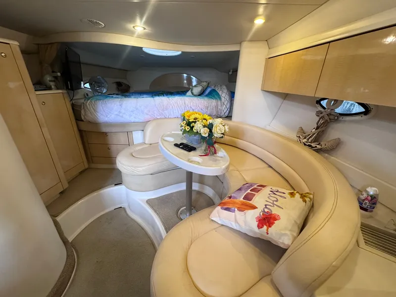 Slide: The Image of Interior of a 2001 Maxum 3500 SCR with cozy seating area, table, and bed in the background. - 12