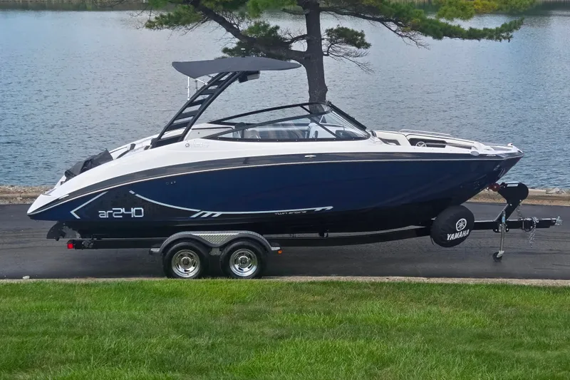 The Image of 2016 Yamaha Boats AR240 on trailer by a lake, showcasing sleek design and modern features. - 0