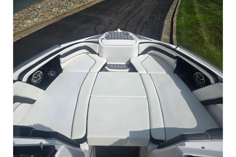 Slide: The Image of 2016 Yamaha Boats AR240 bow seating area with white upholstery and speakers. - 18