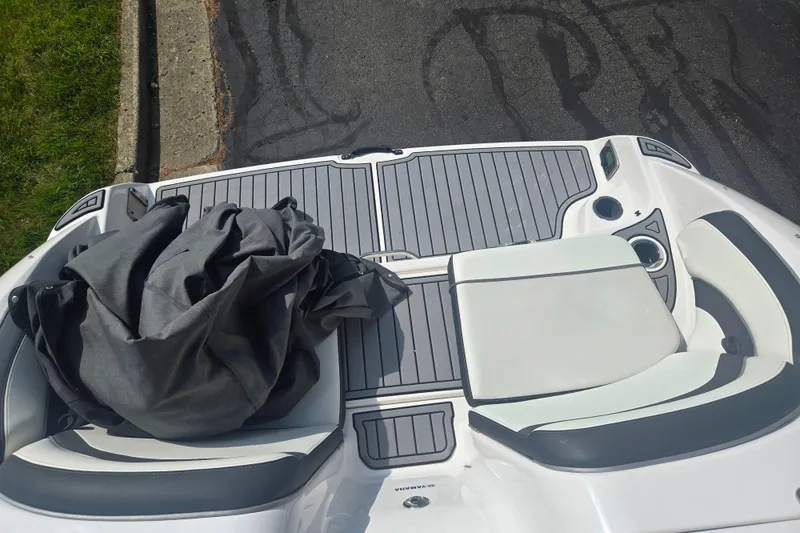 Slide: The Image of 2016 Yamaha AR240 boat deck with seating and cover, parked on pavement. - 25