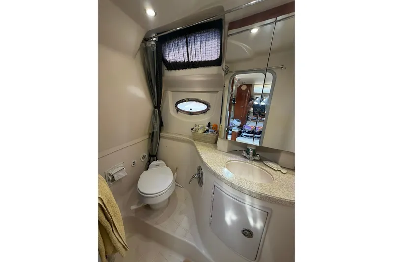 Slide: The Image of 2006 Regal 3360 Window Express yacht bathroom with toilet, sink, mirror, and porthole window. - 31
