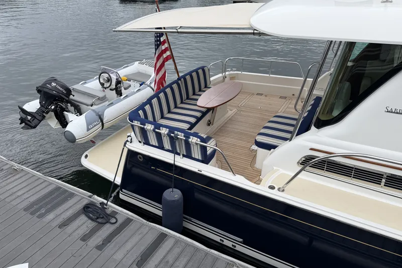 Slide: The Image of 2018 Sabre 48 Salon Express yacht with striped seating and attached dinghy at dock. - 27