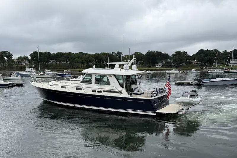 Slide: The Image of 2018 Sabre 48 Salon Express yacht cruising in a scenic harbor with overcast skies. - 32
