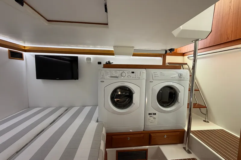 Slide: The Image of Laundry area in 2018 Sabre 48 Salon Express yacht with washer, dryer, and TV. - 24