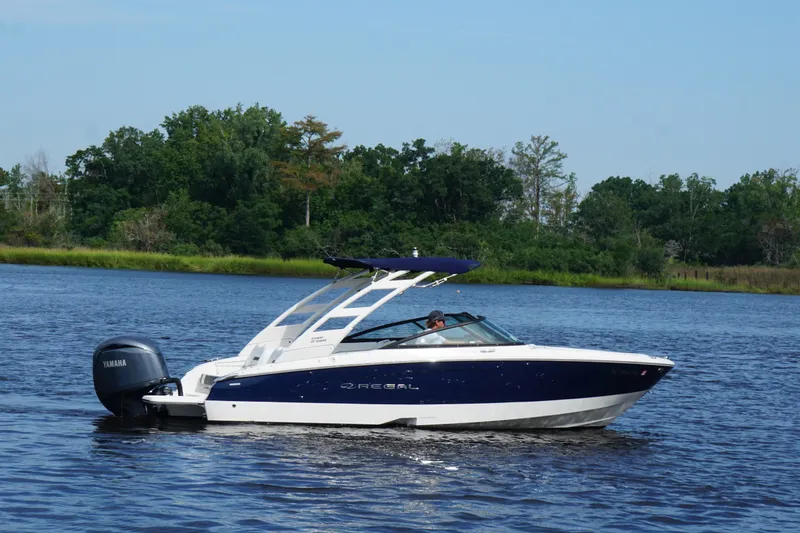 Slide: The Image of 2024 Regal LX2 boat cruising on a serene lake with lush green trees in the background. - 4