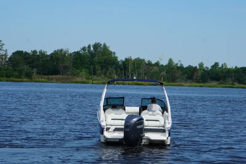 Slide: The Image of 2024 Regal LX2 boat cruising on a serene lake with lush green shoreline. - 8