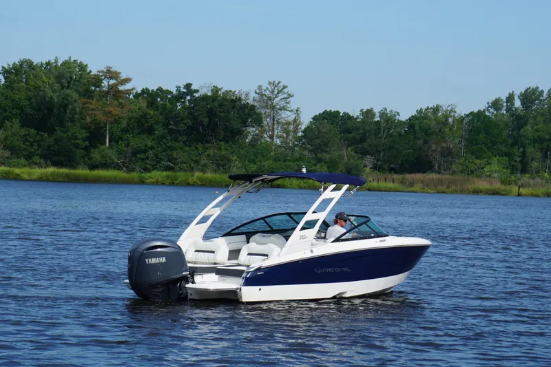 Slide: The Image of 2024 Regal LX2 boat cruising on a serene lake with lush green trees in the background. - 3