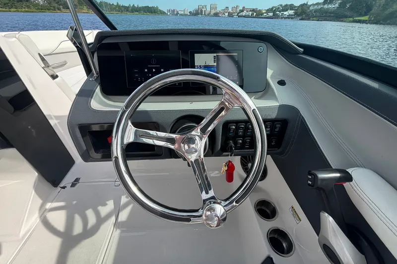 Slide: The Image of 2024 Regal LX2 boat dashboard with steering wheel and digital display on a lake. - 11