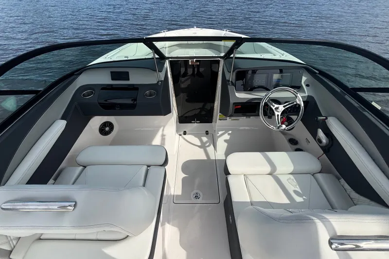 Slide: The Image of 2024 Regal LX2 boat interior with sleek white seating and modern dashboard on water. - 17