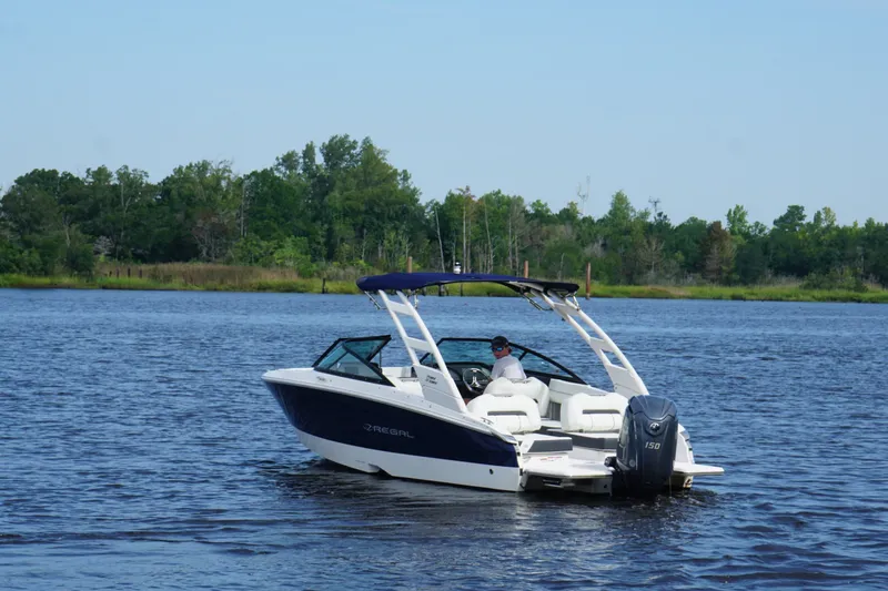 Slide: The Image of 2024 Regal LX2 boat cruising on a serene lake with lush green trees in the background. - 6