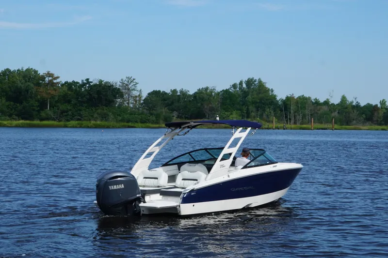 Slide: The Image of 2024 Regal LX2 boat cruising on a serene lake with lush green shoreline. - 9