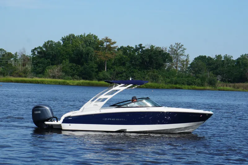 Slide: The Image of 2024 Regal LX2 boat cruising on a serene lake with lush green trees in the background. - 7