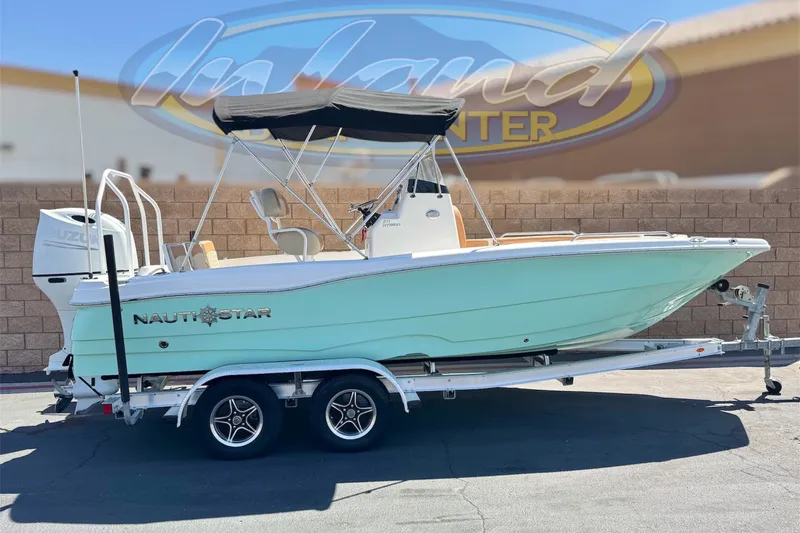 The Image of 2024 NauticStar 211 Hybrid boat on trailer, featuring a sleek design and outboard motor. - 0