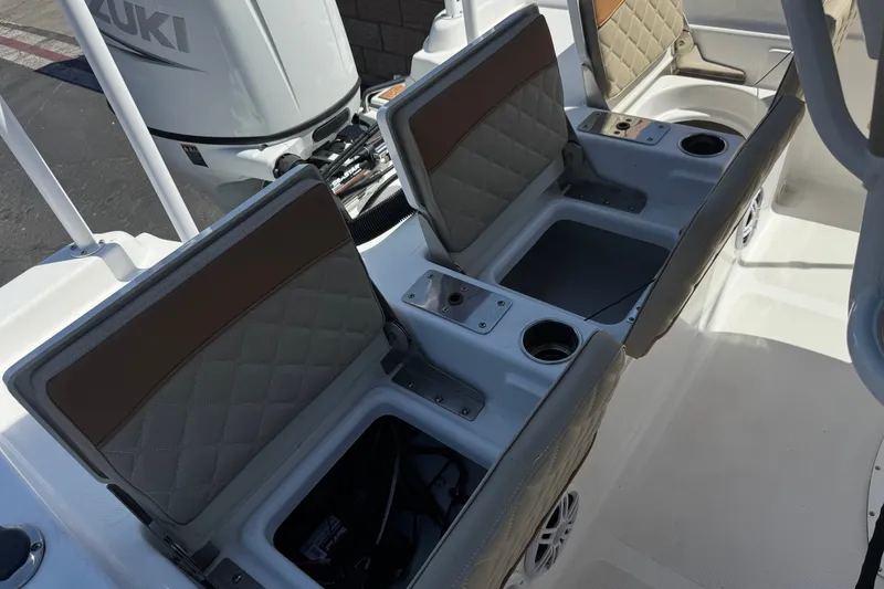 Slide: The Image of 2024 NauticStar 211 Hybrid boat interior with open storage compartments and Suzuki engine. - 21