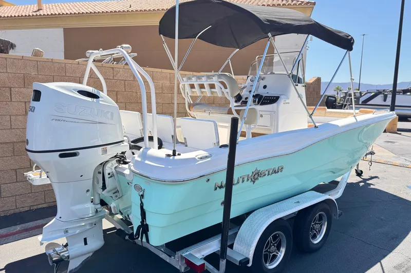 Slide: The Image of 2024 NauticStar 211 Hybrid boat with Suzuki engine on trailer, parked outdoors. - 5