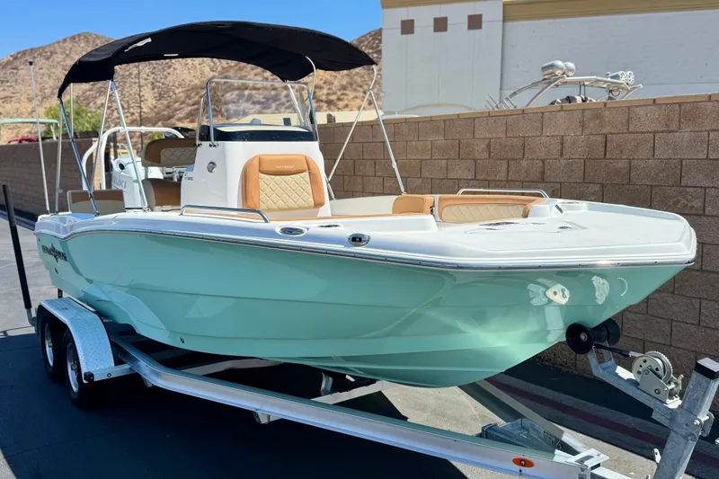 Slide: The Image of 2024 NauticStar 211 Hybrid boat on trailer, featuring sleek design and mint green hull. - 1