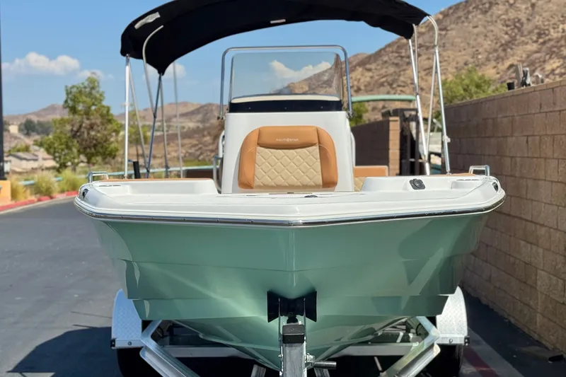Slide: The Image of 2024 NauticStar 211 Hybrid boat on trailer, scenic mountain backdrop. - 2