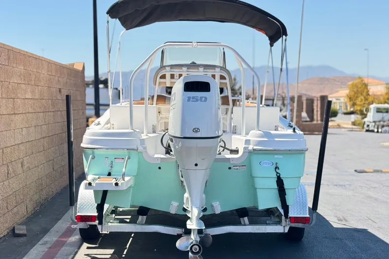 Slide: The Image of 2024 NauticStar 211 Hybrid boat with outboard motor on trailer, parked outdoors. - 4