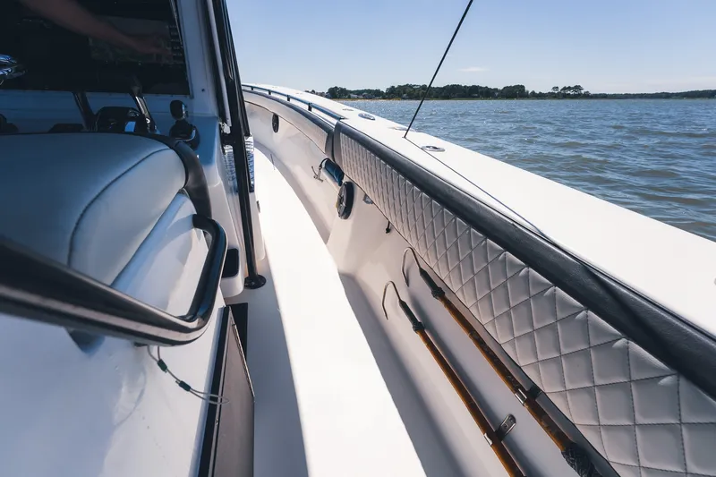 Slide: The Image of 2015 SeaHunter 37 Tournament boat interior with quilted upholstery and fishing rods, on calm water. - 21