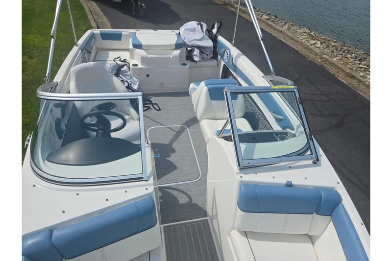 Slide: The Image of 2013 Bayliner 195 Bowrider boat interior with blue and white seating, near water. - 18