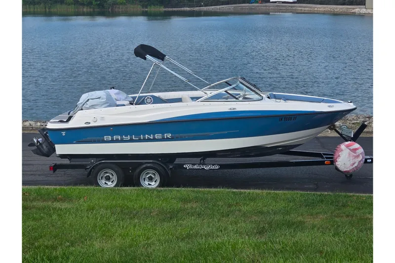 The Image of 2013 Bayliner 195 Bowrider boat on trailer by a lake. - 0
