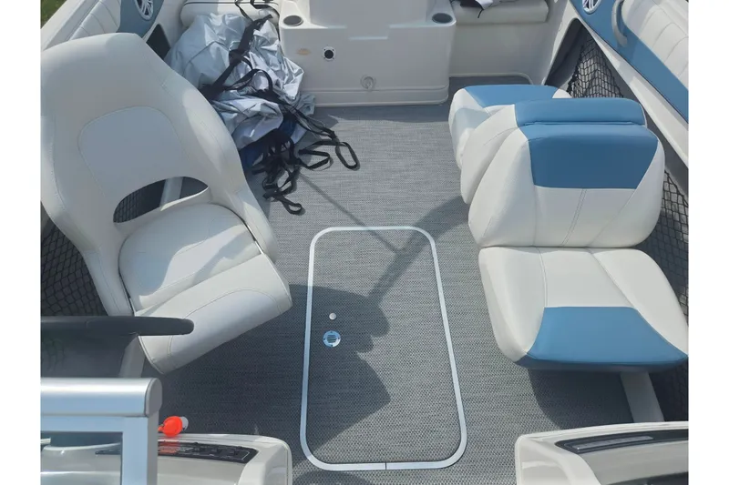 Slide: The Image of 2013 Bayliner 195 Bowrider interior with white and blue seating, gray flooring. - 19