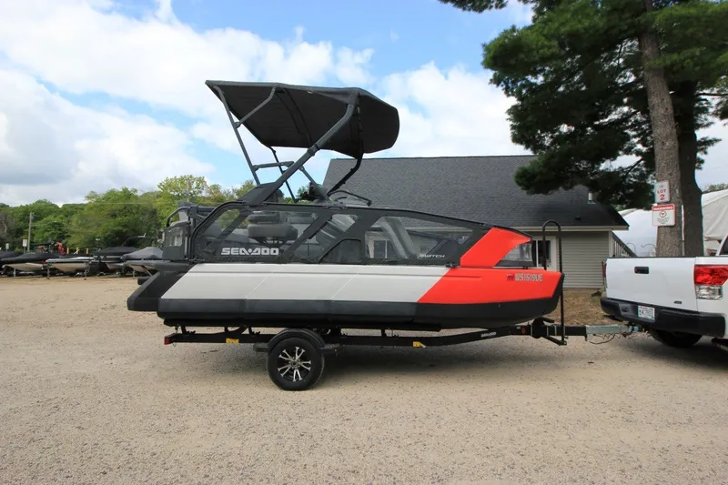 The Image of 2022 Sea-Doo Switch Sport 18 on trailer, parked outdoors near trees and buildings. - 0