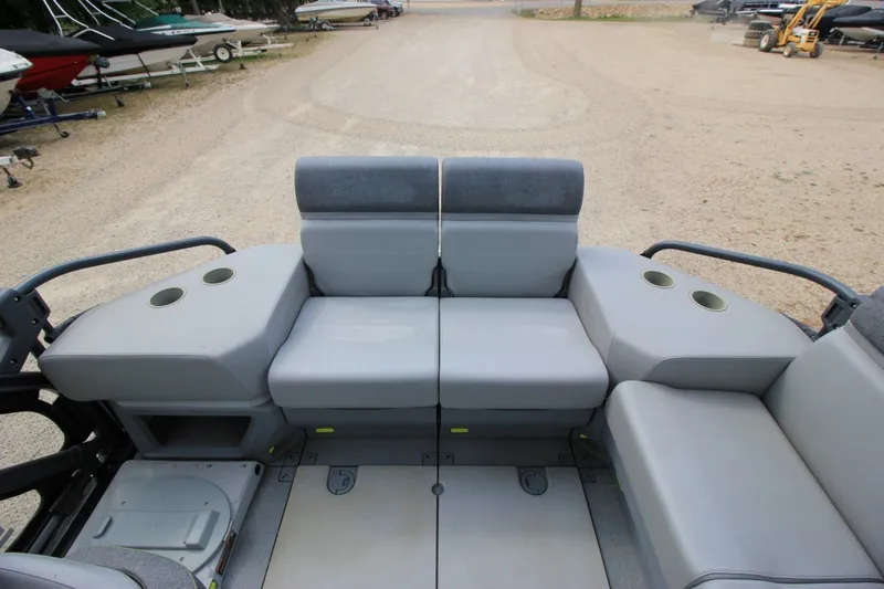 Slide: The Image of 2022 Sea-Doo Switch Sport 18 interior seating with cup holders, parked on gravel. - 10
