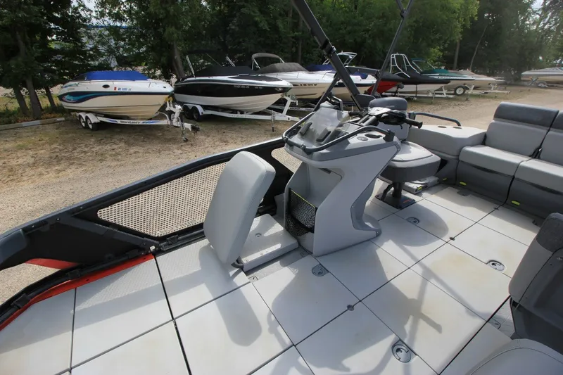 Slide: The Image of 2022 Sea-Doo Switch Sport 18 interior with steering console and seating, parked among other boats. - 13