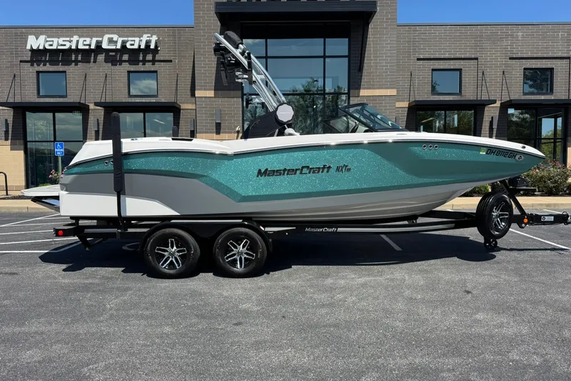 Slide: The Image of 2022 MasterCraft NXT22 boat on trailer, parked outside MasterCraft building. - 2