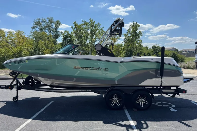 Slide: The Image of 2022 MasterCraft NXT22 boat on trailer, parked outdoors under a clear blue sky. - 6