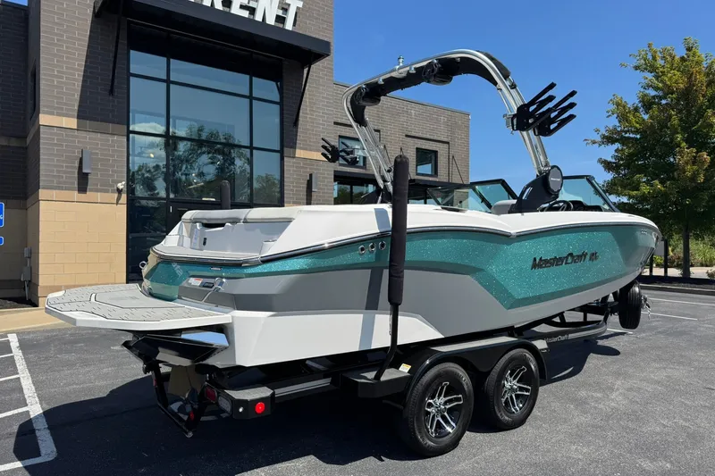 Slide: The Image of 2022 MasterCraft NXT22 boat on trailer, parked outside a modern building. - 3