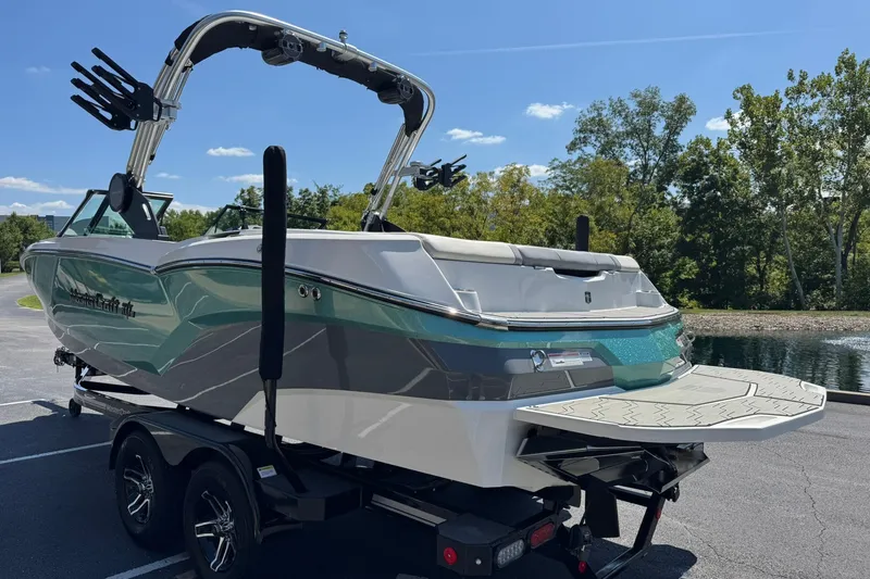 Slide: The Image of 2022 MasterCraft NXT22 boat on trailer, parked near a scenic lake. - 5