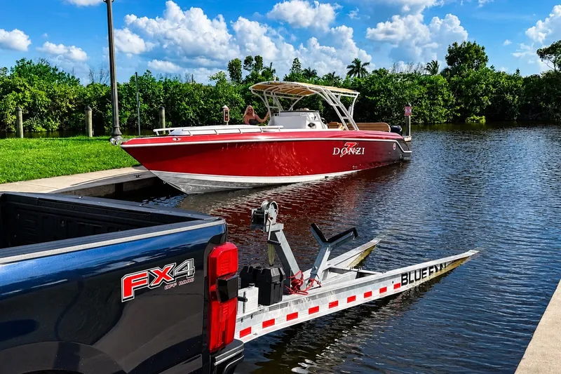Slide: The Image of 2006 Donzi 38 ZFX Cuddy boat on water near a dock, with a truck and trailer. - 21