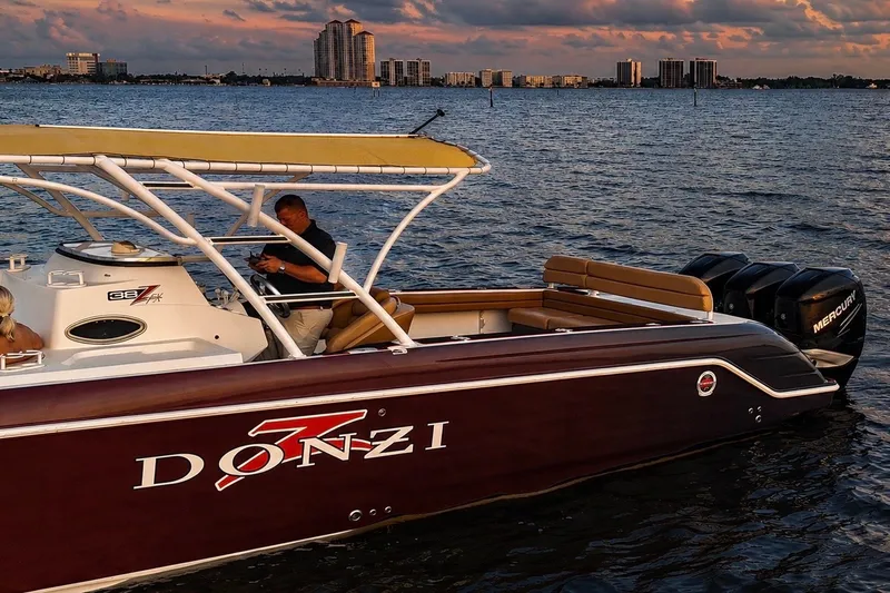 Slide: The Image of 2006 Donzi 38 ZFX Cuddy boat on water at sunset with city skyline. - 25