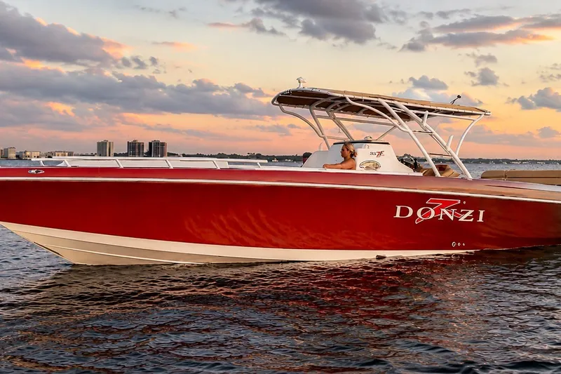 The Image of 2006 Donzi 38 ZFX Cuddy boat cruising at sunset on calm waters. - 0