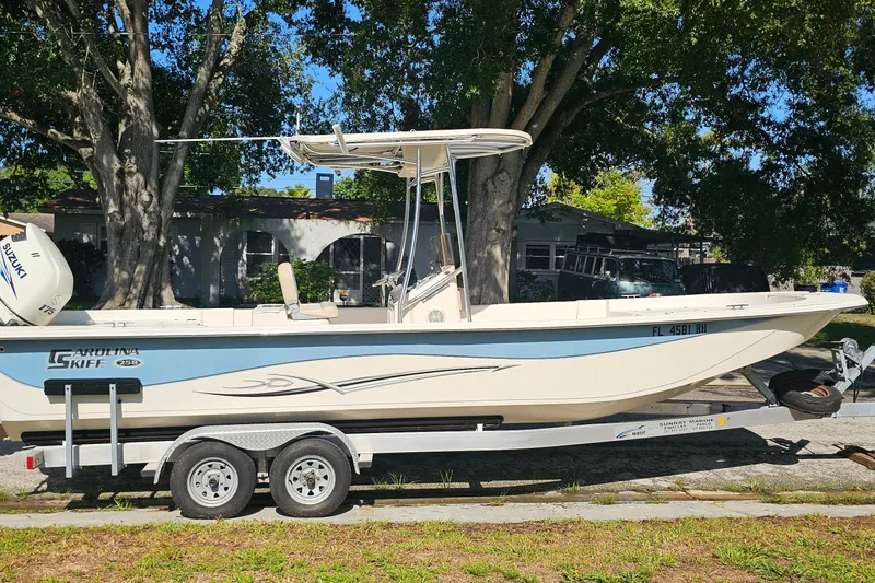 The Image of 2016 Carolina Skiff 258 DLV boat on trailer, parked under trees. - 4