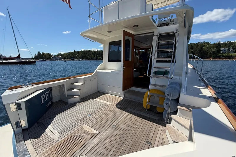 Slide: The Image of York's Marine 46 Flybridge Cruiser 2013, spacious deck with wooden flooring, docked on calm waters. - 10