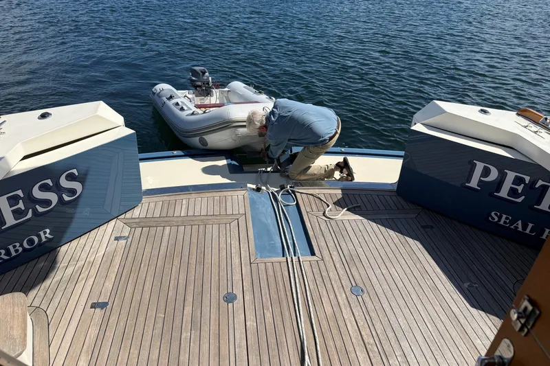Slide: The Image of Man securing dinghy to York's Marine 46 Flybridge Cruiser, 2013, on wooden deck. - 28