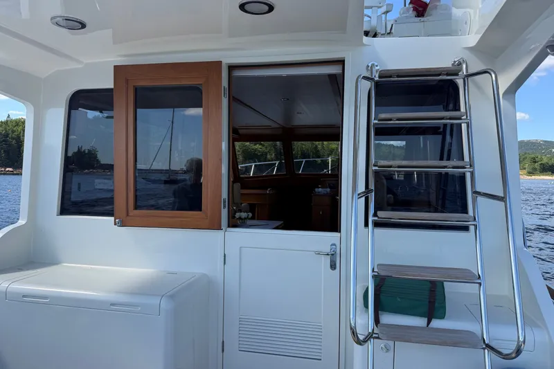 Slide: The Image of 2013 York's Marine 46 Flybridge Cruiser with ladder and wooden door, docked by scenic waters. - 11