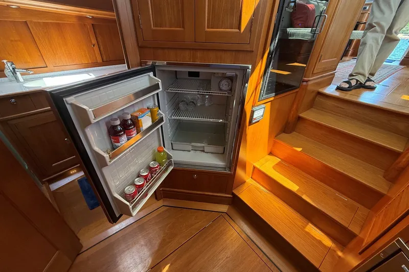 Slide: The Image of Open fridge in 2013 York's Marine 46 Flybridge Cruiser, showcasing beverages and wooden interior. - 44