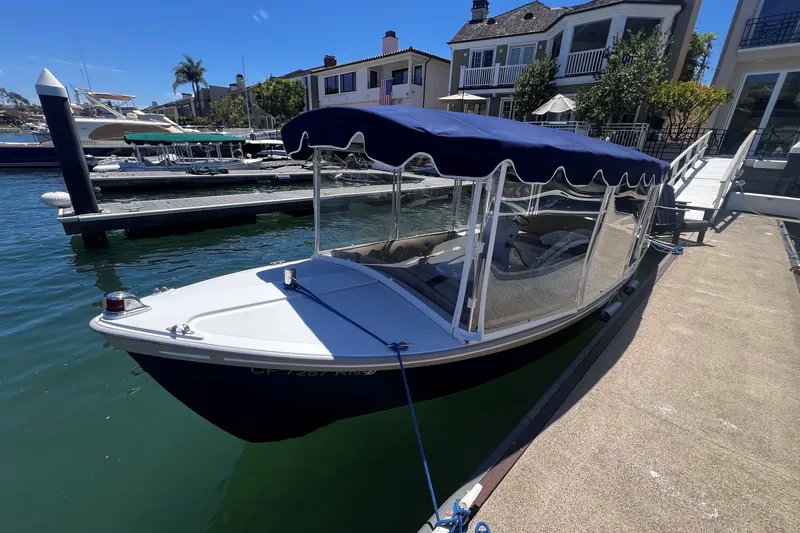 Slide: The Image of Electric Duffy 21 Old Bay boat docked, featuring a blue canopy and clear side panels. - 1