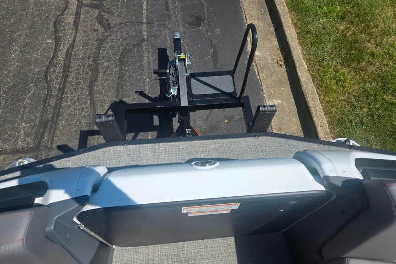 Slide: The Image of 2024 Manitou Cruise boat on trailer, viewed from above, parked on asphalt. - 24