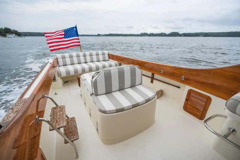 Slide: The Image of 2000 Hinckley Picnic Boat 36 Classic with striped seating and American flag on open water. - 33