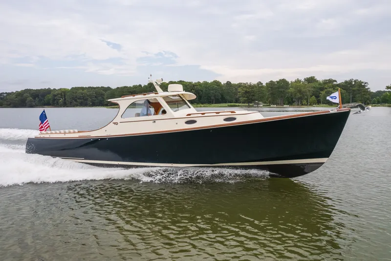 The Image of 2000 Hinckley Picnic Boat 36 Classic cruising on a serene lake with lush green shoreline. - 0
