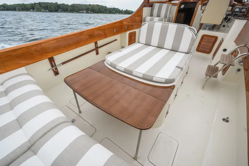 Slide: The Image of 2000 Hinckley Picnic Boat 36 Classic with striped cushions and wooden table on deck. - 22