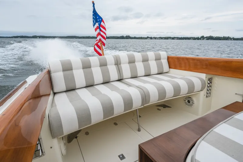 Slide: The Image of Hinckley Picnic Boat 36 Classic, 2000 model, with striped seating and American flag on open water. - 24