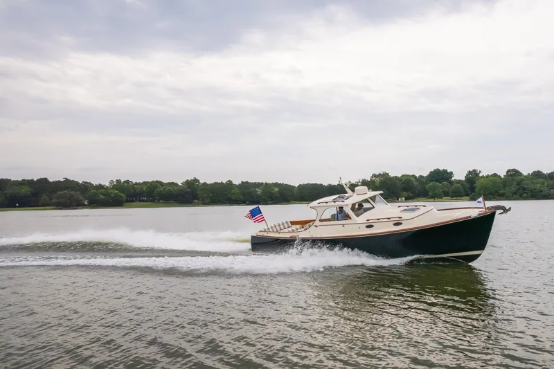 Slide: The Image of 2000 Hinckley Picnic Boat 36 Classic cruising on a serene lake under a cloudy sky. - 14