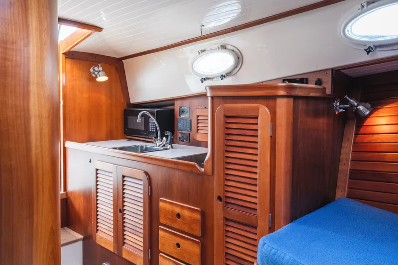 Slide: The Image of Interior of 2000 Hinckley Picnic Boat 36 Classic with wooden cabinetry and compact kitchen area. - 55