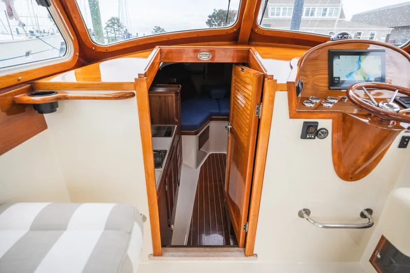 Slide: The Image of Interior view of 2000 Hinckley Picnic Boat 36 Classic, showcasing wooden helm and cabin entrance. - 46